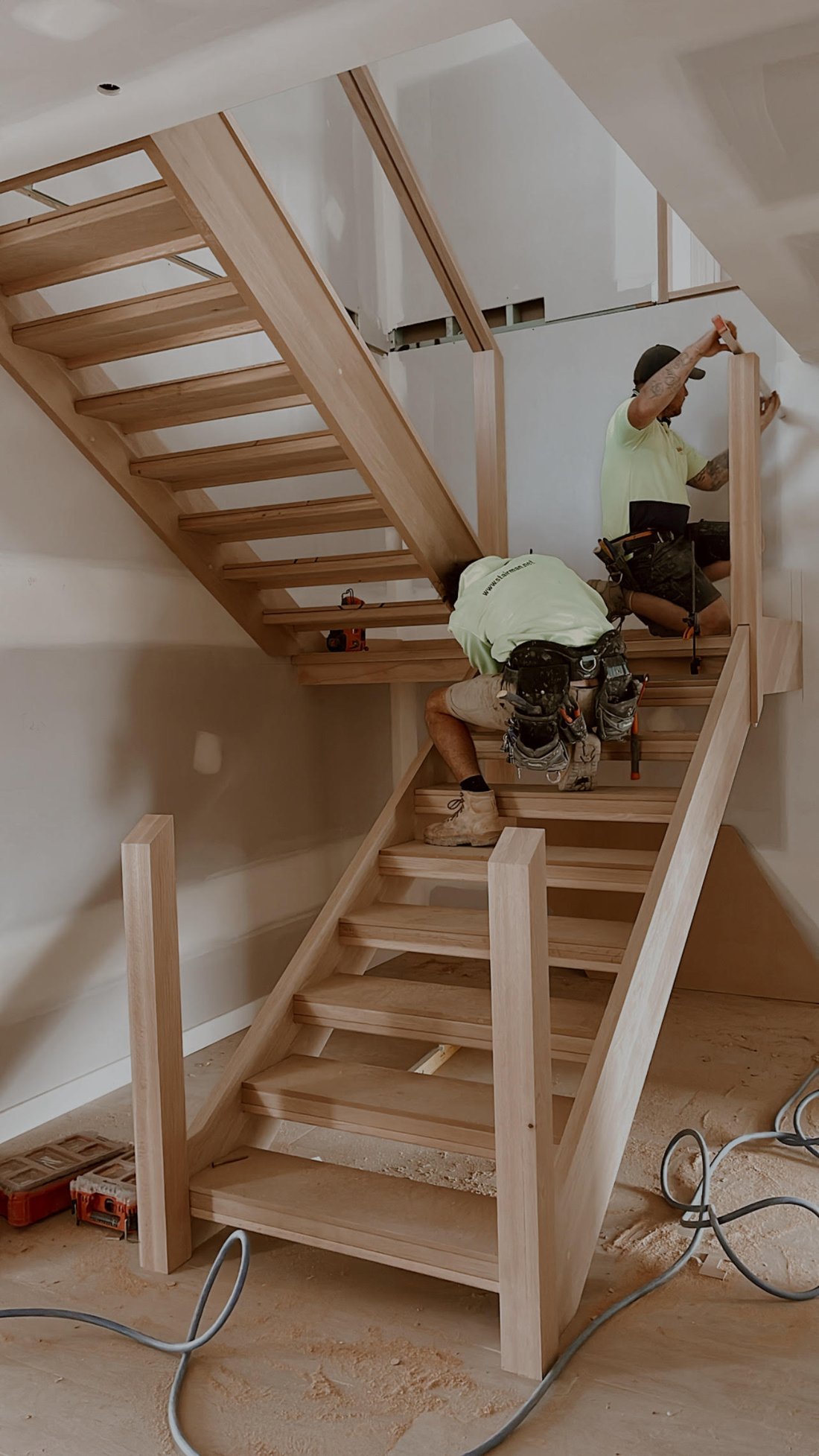 Custom timber staircase being installed by Impact Homes Co.